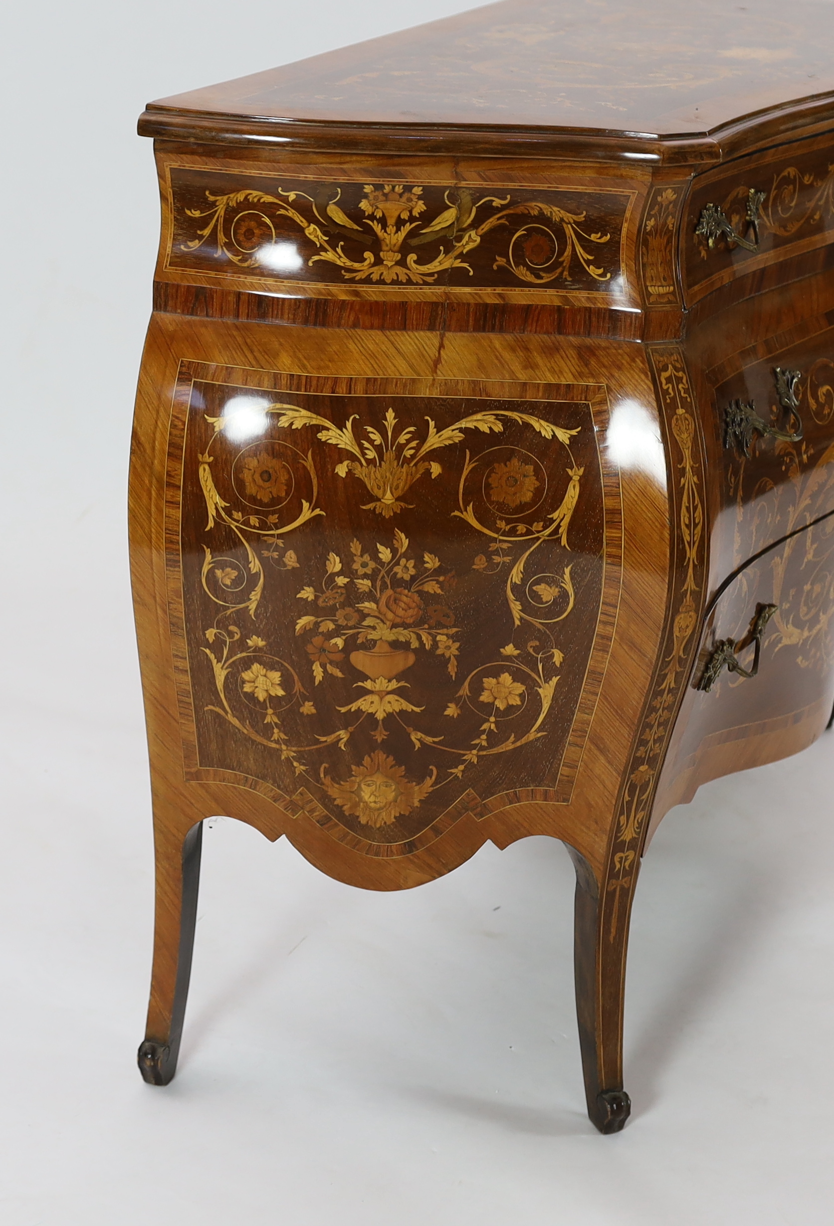 A Continental marquetry inlaid serpentine bombé commode, 130cm wide, 54cm deep, 94cm high